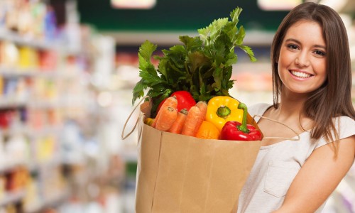woman holding grocery bag full of produce