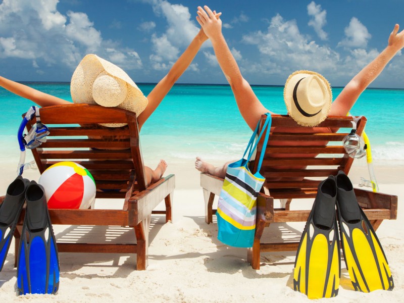 couple in beach chairs with arms in air