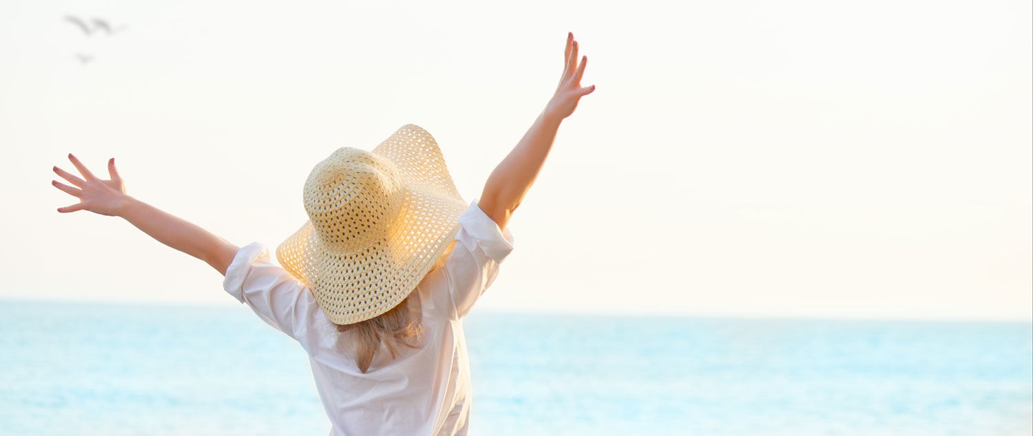 woman wearing sunhat throwing hands in air