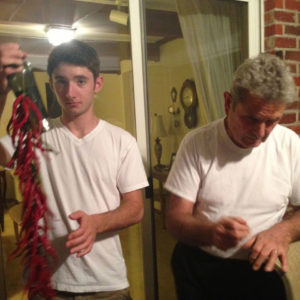 janet's son and father stringing up dried cayenne peppers from the farm